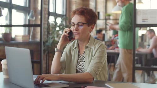 Woman Working on Laptop and Talking on Phone
