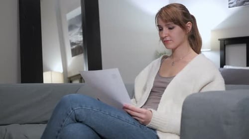 Woman Reading Papers on Couch in Bright Living Room