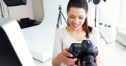 Woman Holding Camera Looking at Computer Monitor