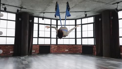 Woman Practices Aerial Yoga Suspended From Hammock