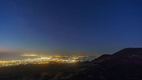 Time lapse from day to night with view at city with milky way, Catania, Sicily, Italy