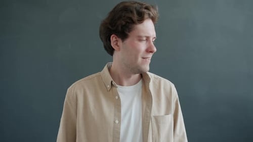 Young Man Looks Around Smiling and Shakes Head