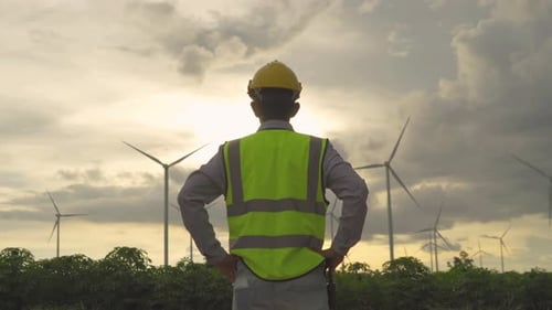 Portrait of Asian windmill engineer man, worker working on site at wind turbines field