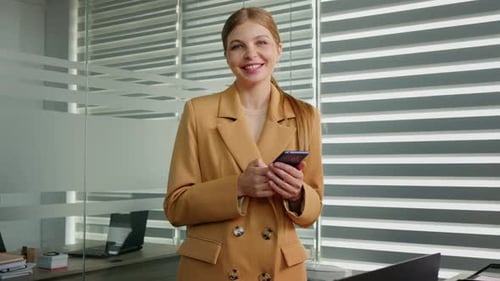 Woman Using Phone and Smiling in Modern Office