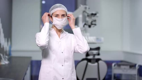 Portrait of Female Dentist Putting on Face Mask and Posing