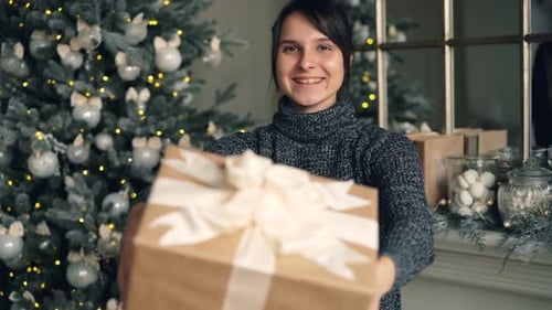 Woman Offering Christmas Gift in Festive Home Setting