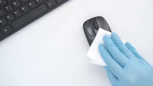 Gloved Hand Sanitizing Computer Mouse on Desk