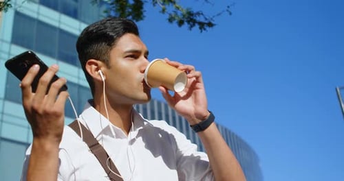 Man Using Smartphone While Drinking Coffee Outdoors