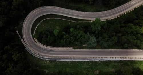 Luftaufnahme von der Drohne der Curve Road mit einem Auto auf dem Berg mit grünem Wald in Russland