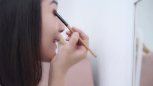 Woman Applying Eyeshadow in Mirror at Home