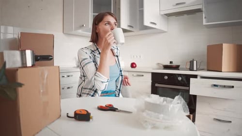 Woman Takes Coffee Break While Packing Kitchen