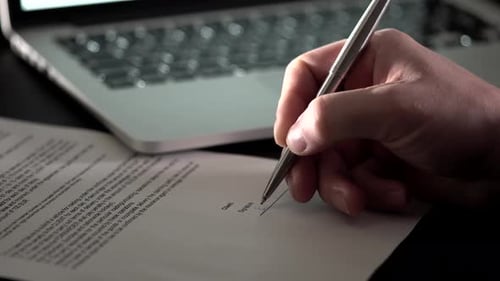 Close Up Shot of the Man's Hand Who Leaves His Signature on Business Document.