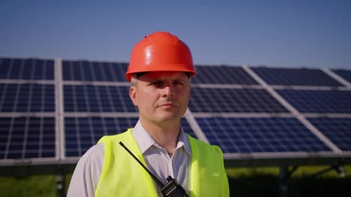 Man in Hard Hat Stands Near Solar Panels