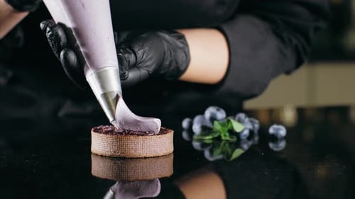 Pastry Chef Decorates Biscuit with Purple Cream From Pastry Bag, Close-up.