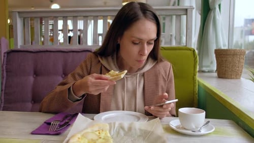 Female Eat Slice Pizza and Use Smartphone in Cafe