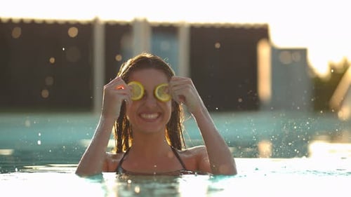 Young Woman with Lemon Slices in Swimming Pool