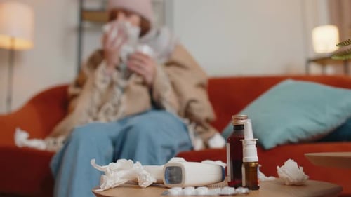 Une femme malade souffrant de rhume ou d'allergies à la maison dans le salon souffle la morve du nez dans la serviette