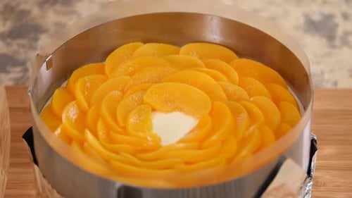 Hands Decorating Peach Cake with Fresh Slices