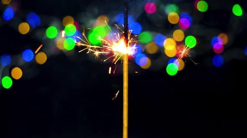 Sparkler Ignites Against Christmas Lights Background