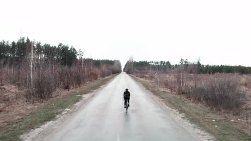 Lone Cyclist Rides Rural Road on Cloudy Day