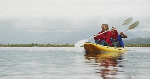 Caucasian couple having a good time on a trip to the mountains, kayaking together on a lake