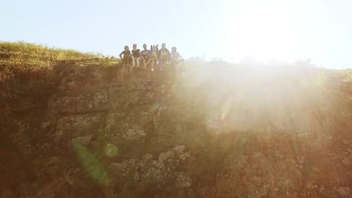 Group of Happy Tourists Sitting on the Cliff Near Precipice Than Waving Hand and Fall Back on