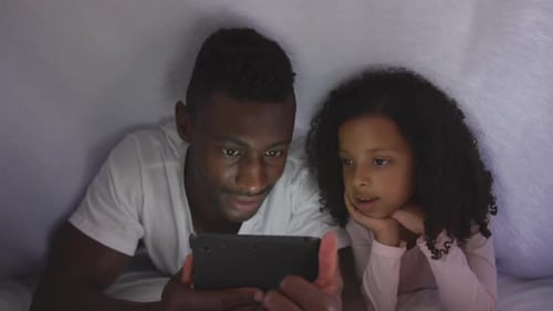 Father and Child Watch Tablet Under Blanket Tent