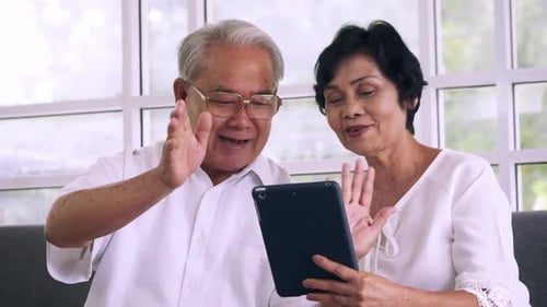 Senior Couple Video Chatting Using Tablet Indoors