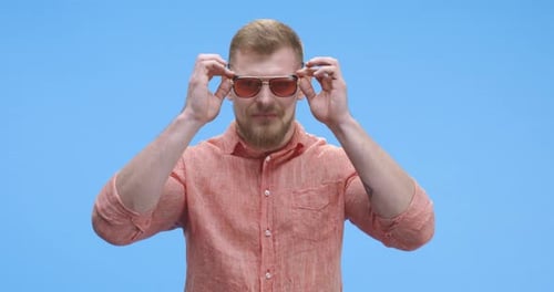 Man with Beard Puts on Pair of Sunglasses