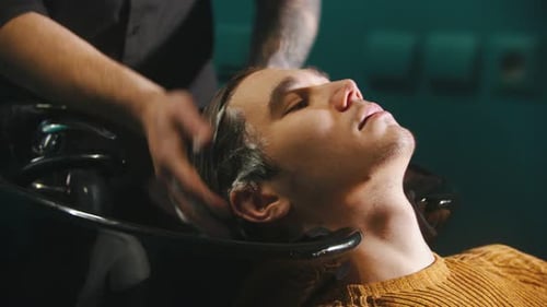 A Young Man Having His Hair Washed with Shampoo in Barbershop