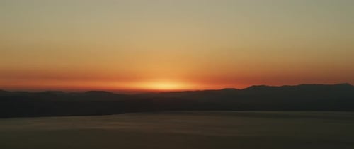 Beautiful landscape with sunset over the big lake and the mountains. Tilting up to down shot.