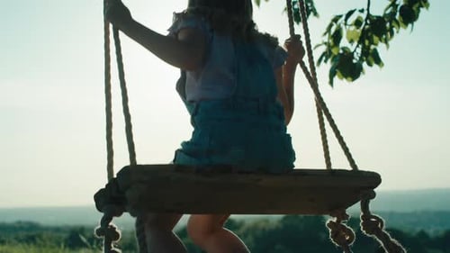 Rear view of swinging girl during the golden hour. Shot with RED helium camera in 4K.