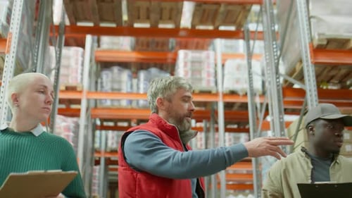 Manager Instructing Multiethnic Coworkers in Warehouse
