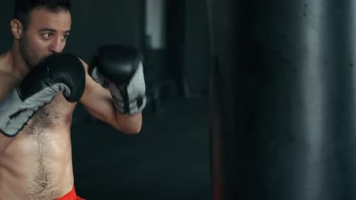 Aggressive Professional Fighter Is Training with a Punching Bag, Inflicting a Furious Blow. The