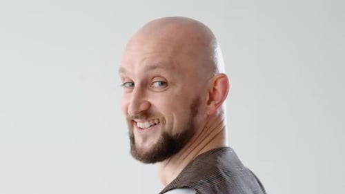 Bald Man Smiles in Brown Vest Close Up