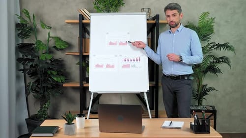 Man teacher listens question tells videocall points marker diagrams on flipchart