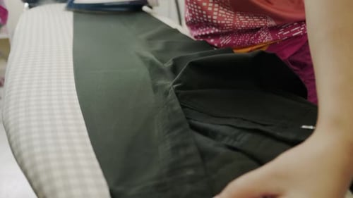 Closeup of a woman ironing clothing by stream iron on board at home