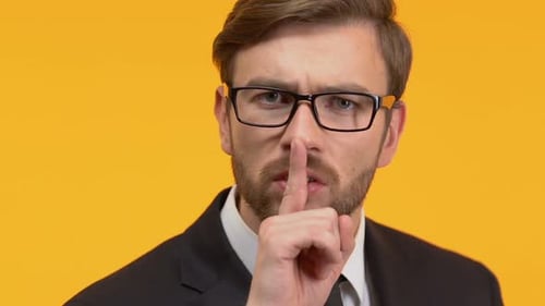 Homme tenant un doigt près de ses lèvres montrant un signe de silence, enquête top secrète
