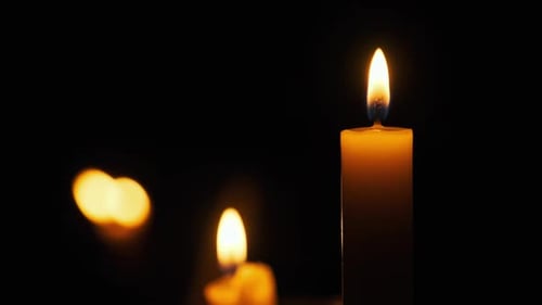 Glowing Candle Flickering in the Darkness