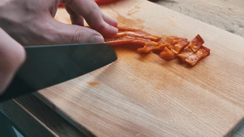 Slicing healthy dinner. Close-up of sliced pepper on a wooden board and a sharp knife. Closeup of ha