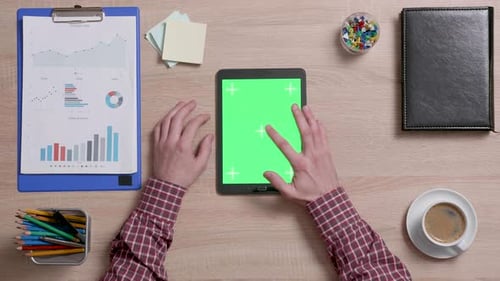 Top View of a Man Tap Multiple Times on the Center of a Green Screen on Tablet