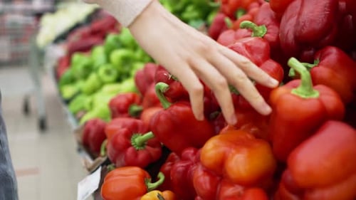 Frau wählt Gemüse in der Nähe der Paprikareihe im Supermarkt
