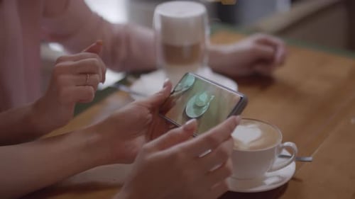 Unrecognizable Women Looking at Photo of Cup of Cappuccino at Cafe