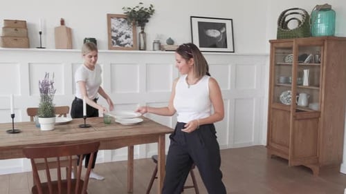 Women Setting Up Dining Room Table