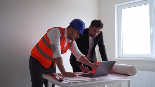 Two Men Reviewing Construction Plans on Laptop