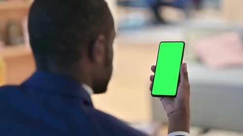 Man Holding Cellphone With Green Screen Indoors