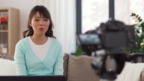 Asian Female Blogger with Camera Recording Video