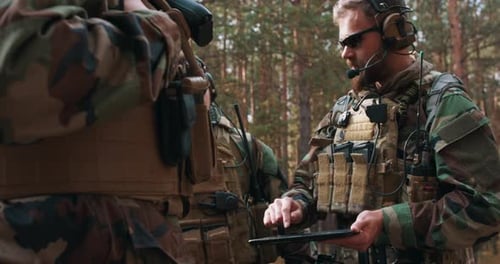 Men in Camouflage Using Tablet in Forest
