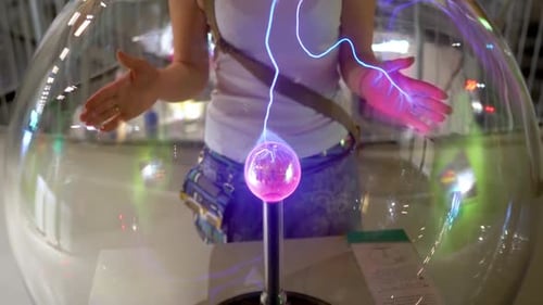 Woman Interacts with Plasma Globe in Science Center