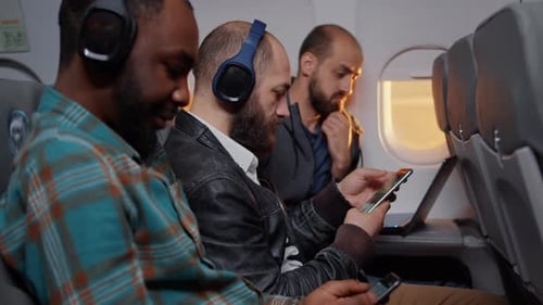 Passengers travel on airplane with phones and laptops